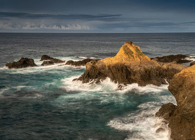 Scenic view of rocks in sea against sky