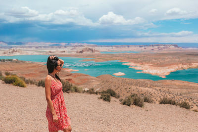 Rear view of woman standing on sand at beach against sky