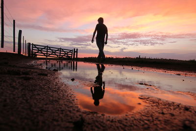 Silhouette man standing on beach against sky during sunset