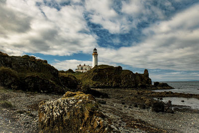 Lighthouse by sea against sky