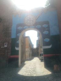 Archway amidst buildings against sky on sunny day