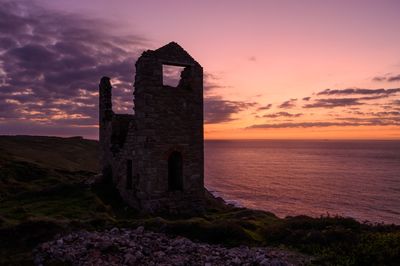 Historic building by sea against sky during sunset