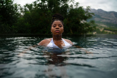 African american female in bikini swimming in clear water in pool during summer vacation in resort in highlands