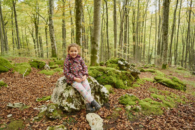 Joyful small kid in warm clothes looking at camera and smiling while