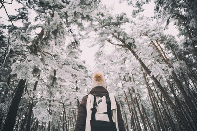 Woman holding umbrella against trees