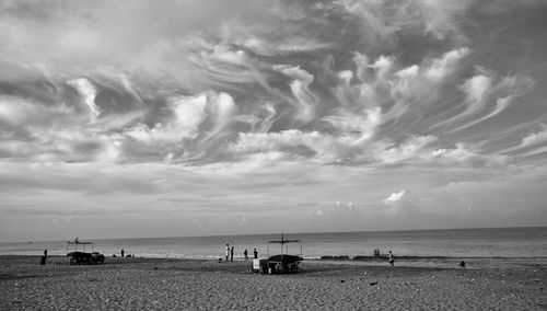 View of calm beach against cloudy sky