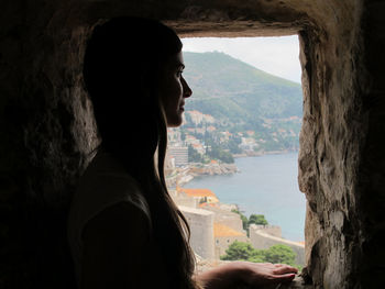 Close-up of young woman looking through window