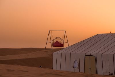 Built structure on beach against sky during sunset