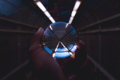 Cropped image of hand holding crystal ball in tunnel