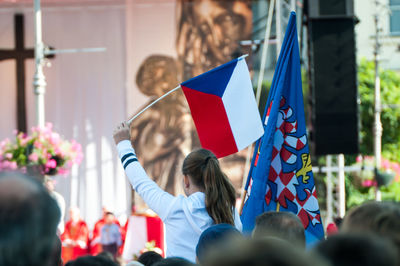 Rear view of people holding flag in city