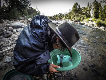 Man looking at water in bowl by stream