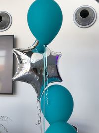 Low angle view of balloons against blue wall