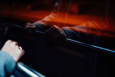 Cropped hand holding railing reflecting on window