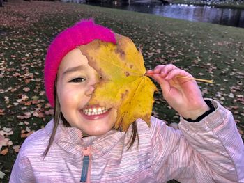 Close-up portrait of a smiling young woman with autumn leaves