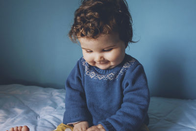 Cute girl sitting on bed at home