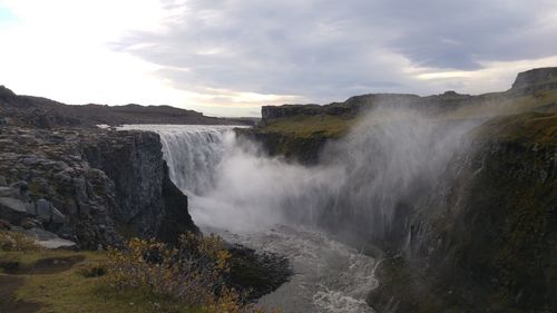 Scenic view of waterfall against sky