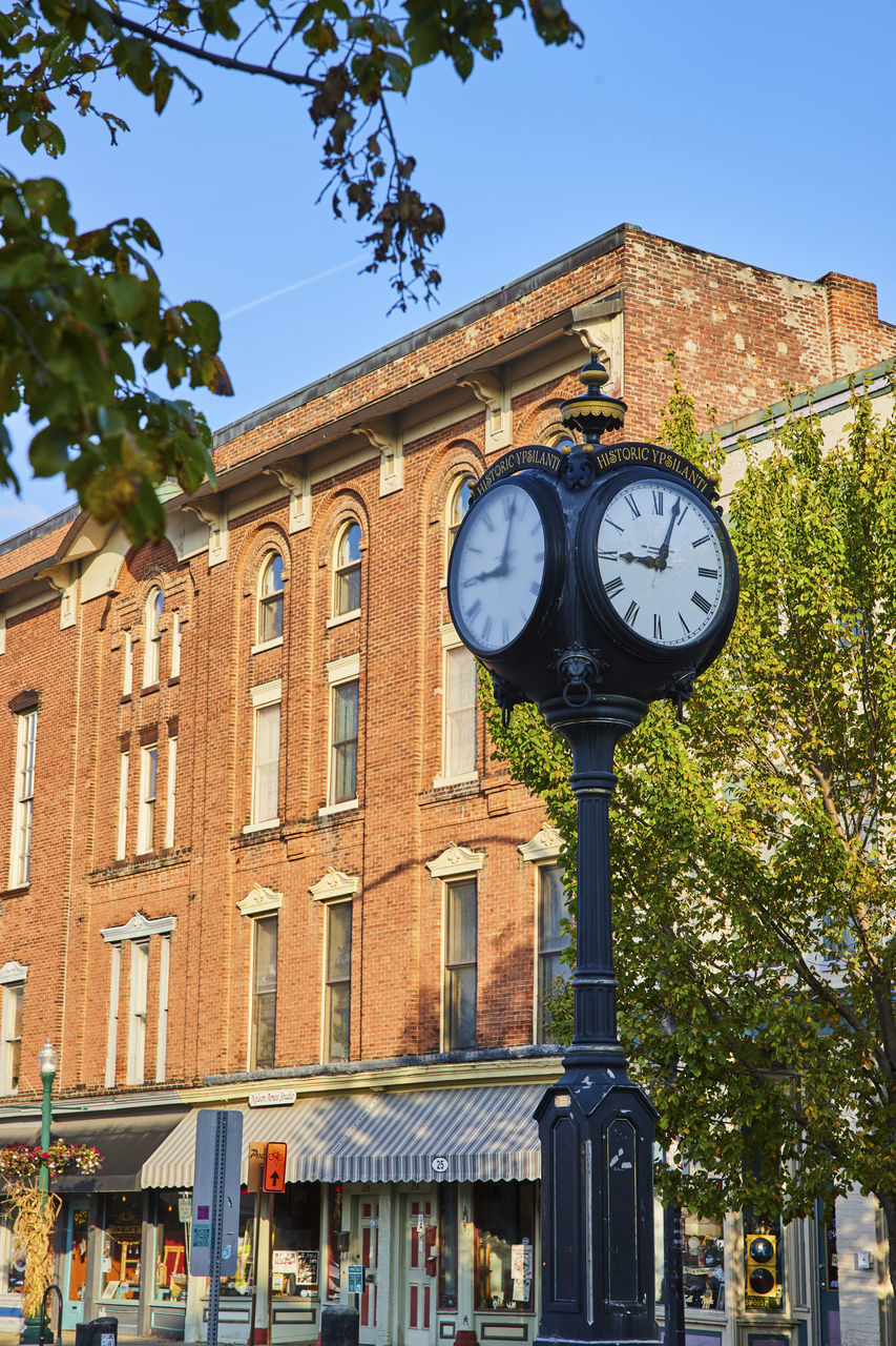 clock, architecture, time, neighbourhood, building exterior, town, built structure, city, clock face, downtown, tree, urban area, building, nature, street, clock tower, plant, travel destinations, sky, day, wall clock, landmark, no people, clear sky, travel, outdoors, tower, transportation, sunny, history, the past, facade, town square, minute hand