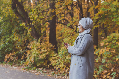 Woman standing by tree during autumn