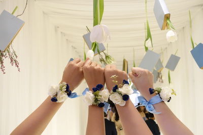 Cropped hands of friends showing flower bracelets 