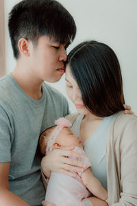 Romantic couple with daughter standing against wall at home