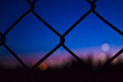 Low angle view of chainlink fence against blue sky
