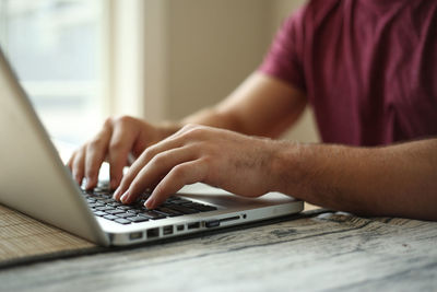 Close-up of man using laptop on table