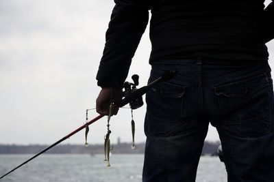 Midsection of man holding umbrella against sky