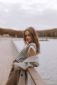Portrait of smiling young woman sitting on pier