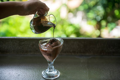 Close-up of hand holding drink on table