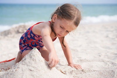 Cute girl playing in sand on beach