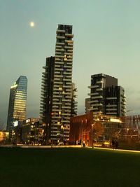 Illuminated buildings in city against clear sky