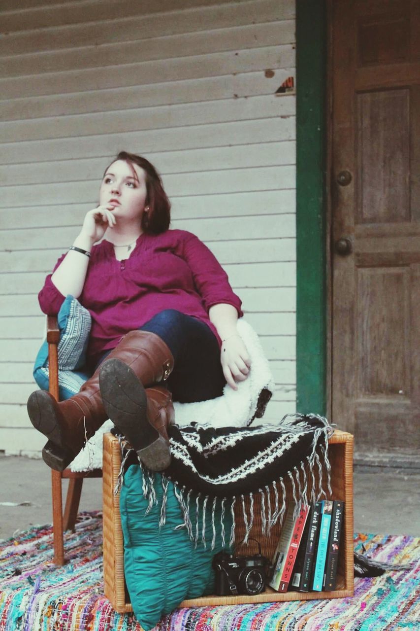 FULL LENGTH OF YOUNG WOMAN SITTING ON CHAIR