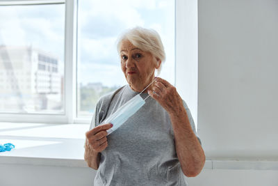 Portrait of woman standing against window