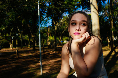 Thoughtful young woman against tree at park