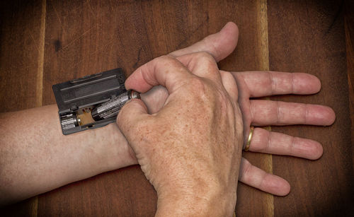 Cropped image of man putting battery on hand over wooden table