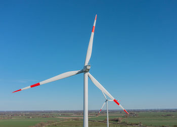 Wind turbines on field against clear blue sky