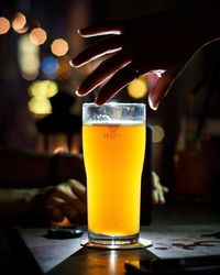 Close-up of hand holding beer glass on table