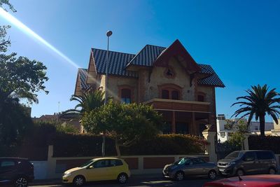 Cars on road by building against clear blue sky