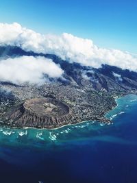 Aerial view of sea and mountains against blue sky