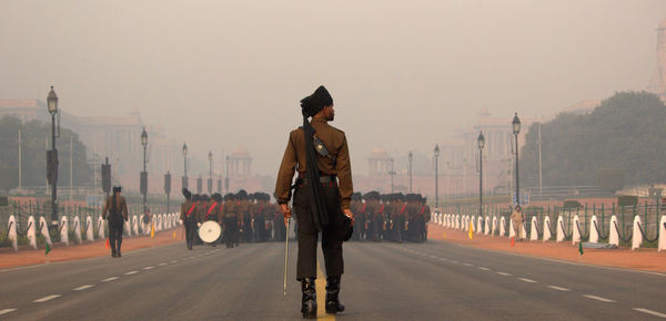 Man standing on road in city against sky