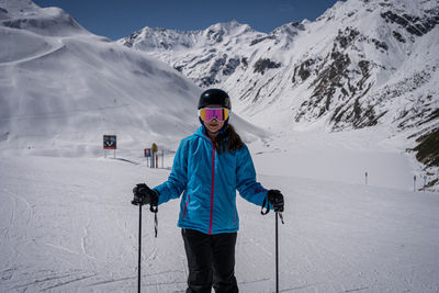 Young women with ski goggles in tirol in blue ski jacket and helmet