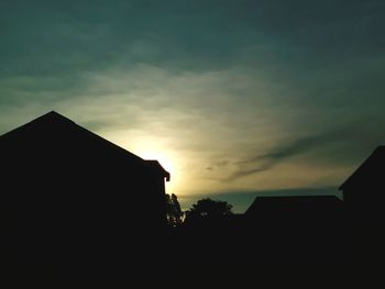 Silhouette houses against sky during sunset