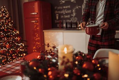 Midsection of man preparing food at kitchen against christmas tree