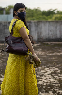 An indian woman in yellow dress and face mask on is going outside after unlock 1.0 of corona virus 