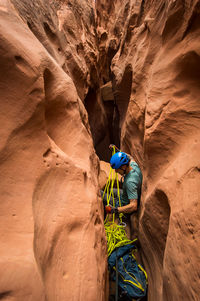 High angle view of man holding ropes while climbing rock