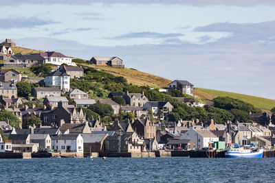 Houses on mountain by sea against sky