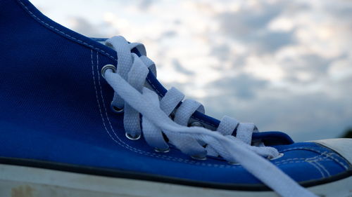 Close-up of shoes on rope against blue sky