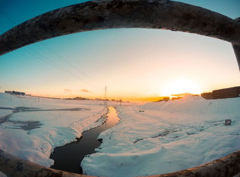 Scenic view of snow covered land against sky during sunset