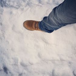 Low section of man walking on snow covered field