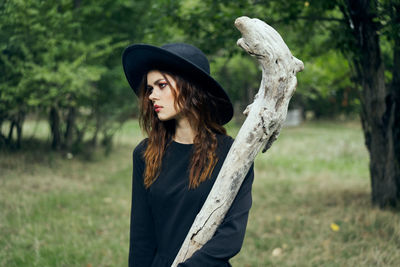 Side view of young woman standing against trees